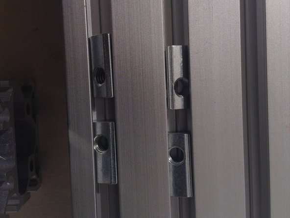 Insert the next 4 spring nuts. When inserting these, have the bolt holes near each other. Use a screwdriver to roll the spring nuts into the slot.