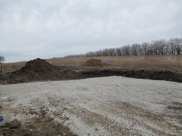 Flatten gravel into a level pad. The foundation formwork will be built on top of this pad.
