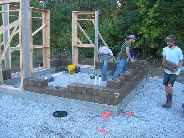 Image 2: People outside the wall feed bricks to people inside the wall. The feeders' job is to make sure that the layers are never waiting for bricks and that they are not laying the bricks in the way of where they need to be stacked.