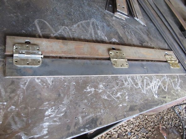 Weld one plate with holes, one without holes, and 3 hinges together as shown, with the plates 1 1/8" apart and the hinge centered.